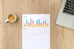 Printed SEO crawl report with charts next to a laptop and coffee