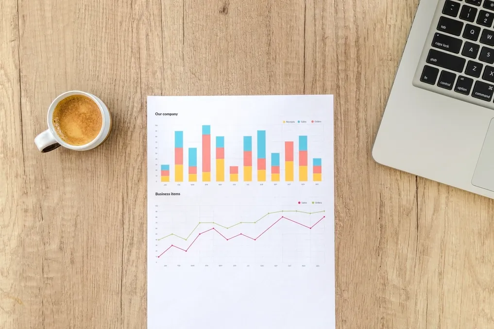 Printed SEO crawl report with charts next to a laptop and coffee