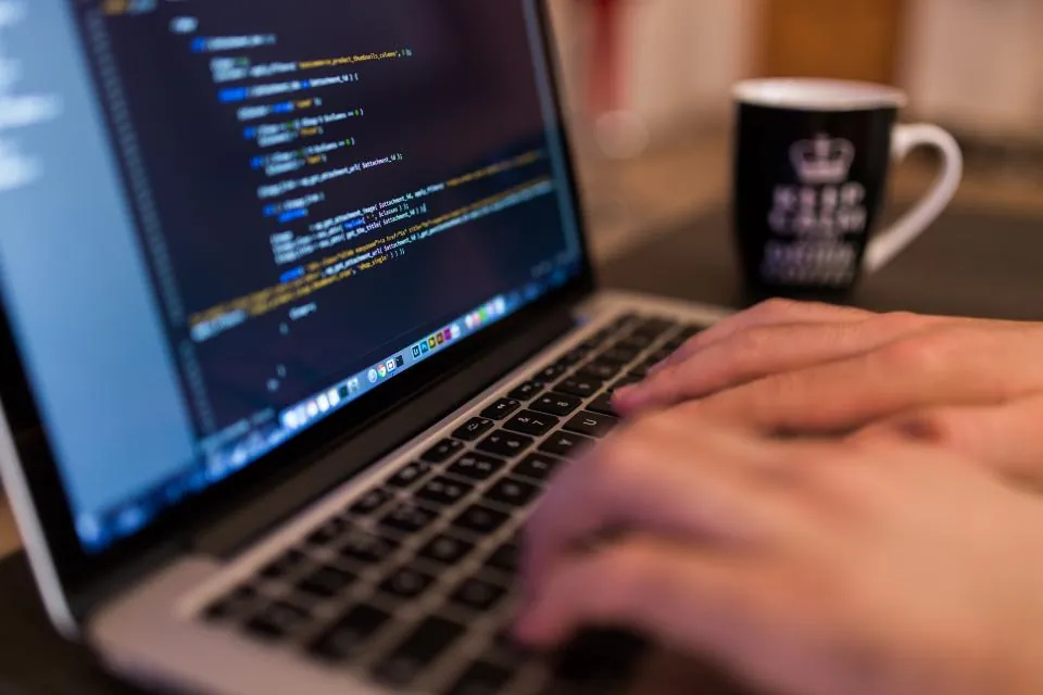 Hands typing JSON-LD schema markup code on a laptop
