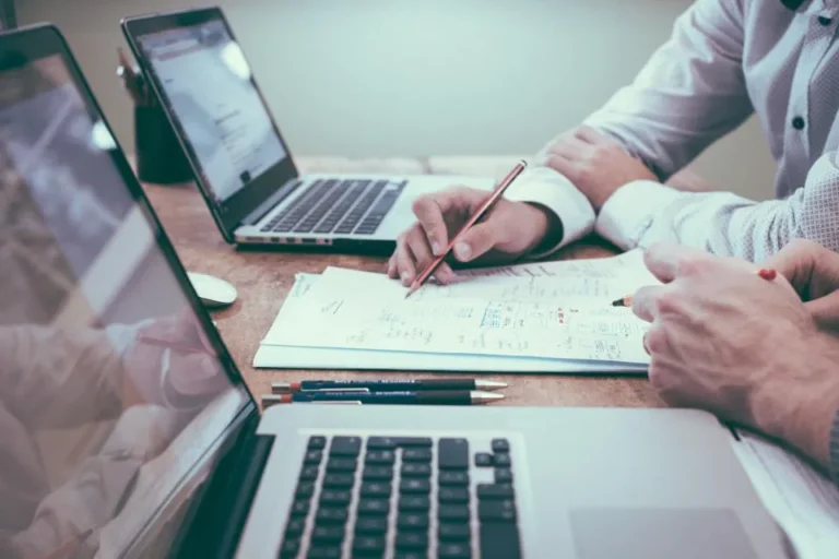 Small business owners working through an SEO audit checklist with laptops and notes